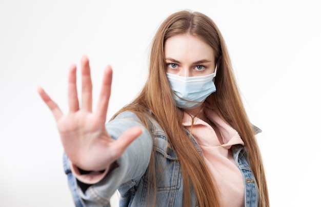 Keep your distance Woman in medical mask showing stop hand gesture isolated on white background