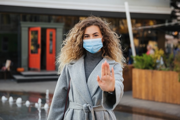 Keep your social distance. woman in virus protection face mask showing gesture Stop Infection.