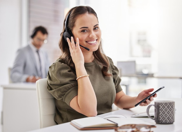 Keeping the channels of communication open for her customers Portrait of a young call centre agent using a cellphone while working in an office