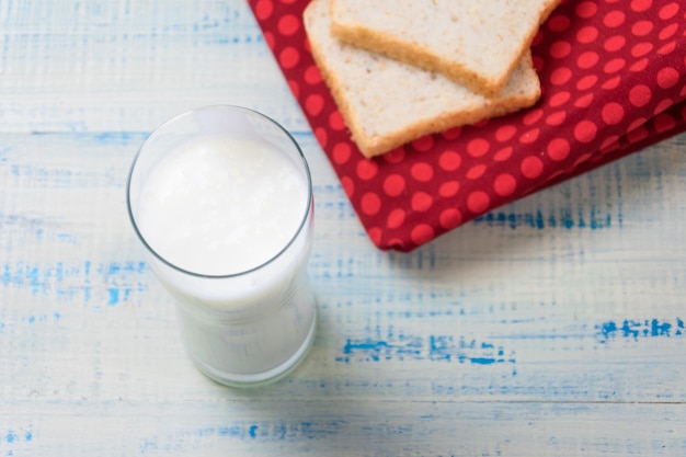 Kefir yogurt in a glass on a background of slices of white bread on a wooden background