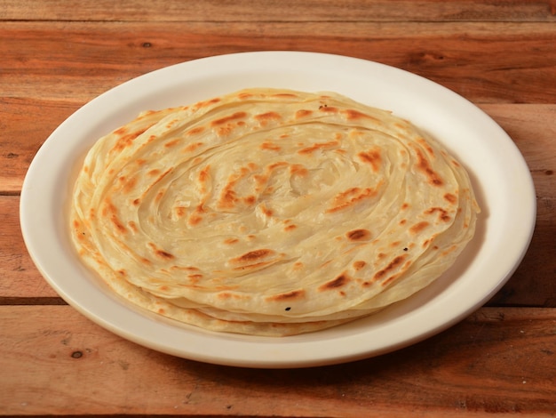 Kerala Paratha a layered flat bread using wheat flour popular dish in south India isolated over a rustic wooden background selective focus