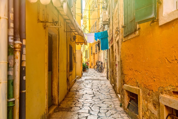 Kerkyra city narrow street view with yellow colorful houses and bikes during sunny day Corfu Island Ionian Sea Greece