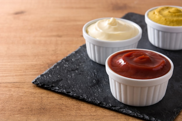 Ketchup,mustard and mayonnaise in a bowls on wooden table