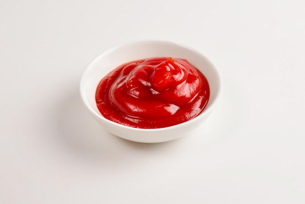 Ketchup in white plate on white background.