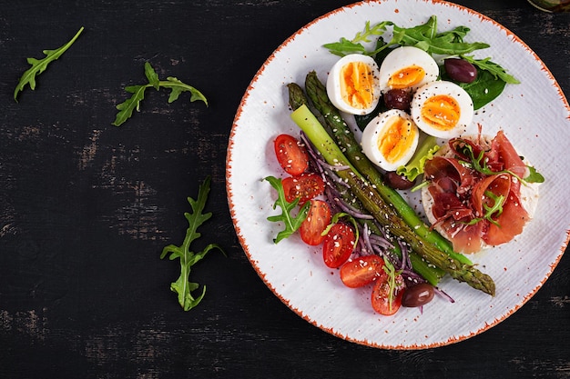 Keto breakfast Fried asparagus with boiled eggs and toast with prosciutto or jamon Ketogenic diet Healthy food Top view flat lay