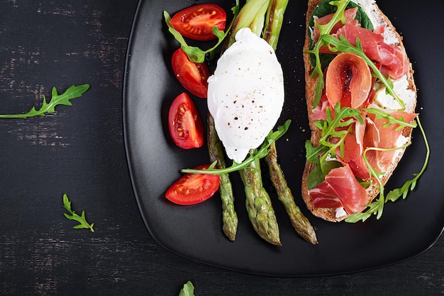 Keto breakfast Fried asparagus with poached egg and toast with prosciutto or jamon Ketogenic diet Healthy food Top view flat lay