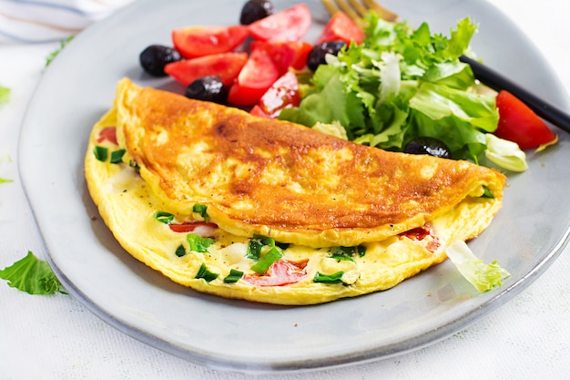 Keto breakfast. Omelette with cheese, tomatoes and green onions on light table. Italian frittata. Keto, ketogenic lunch.