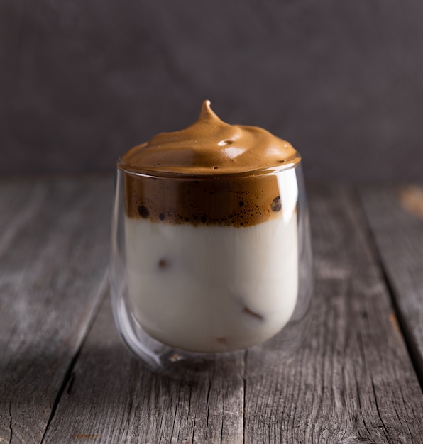 Keto dalgona whipped coffee with milk in a glass on rustic wooden table