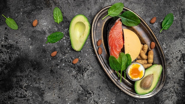 Photo keto diet food salmon avocado cheese egg spinach and nuts ketogenic low carbs diet concept ingredients for healthy foods selection place for text top view