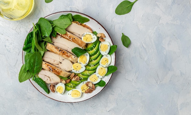 Ketogenic diet avocado grilled chicken fillet quail egg spinach walnut on a light background Low carb high fat breakfast Long banner format top view