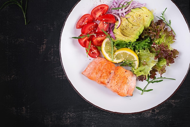 Ketogenic diet breakfast Baked salmon salad with greens tomatoes red onions and avocado Keto paleo lunch Top view overhead