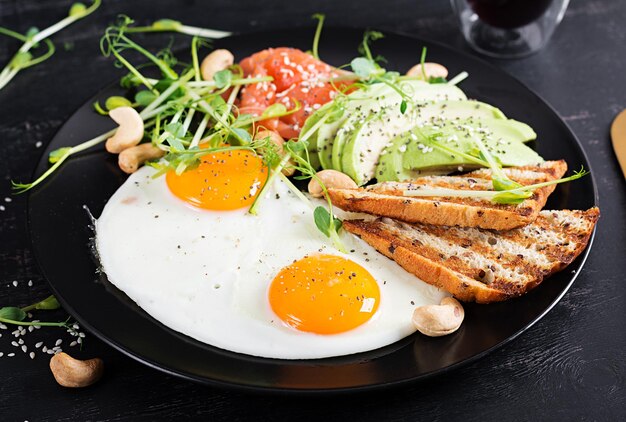 Ketogenic diet breakfast Fried eggs salt salmon with microgreens avocado cashew nuts and keto toast Keto lunch