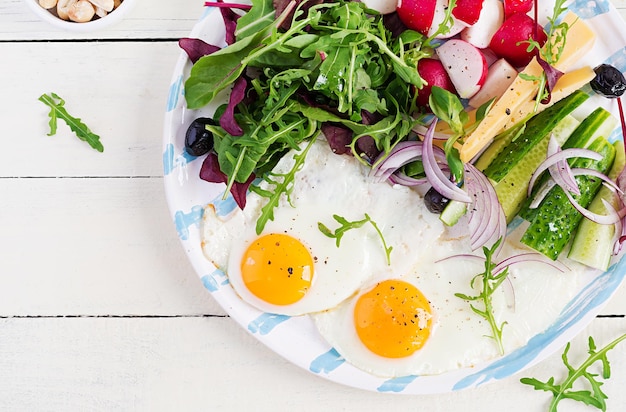 Ketogenic food Fried egg cheese nuts and fresh salad Keto paleo breakfast Top view overhead copy space