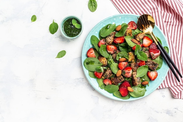 Ketogenic, keto diet. Salad with strawberries, spinach, chicken liver, almond and mint