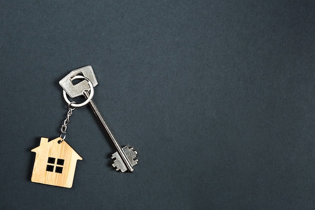 Key chain in the shape of wooden house with key on a black background