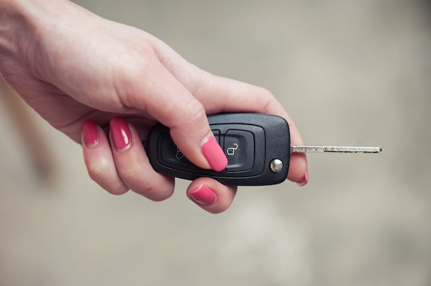 Key from the car in a female hand. Car seller. Opening and signaling. Car selling and present