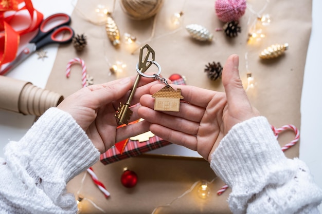 Key to house with keychain on cozy home in gift box with Christmas decor packaging Pack present for New Year Christmas Building project moving to new house mortgage rent purchase real estate