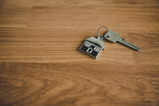 Key and a keychain shaped house on wooden floor in room