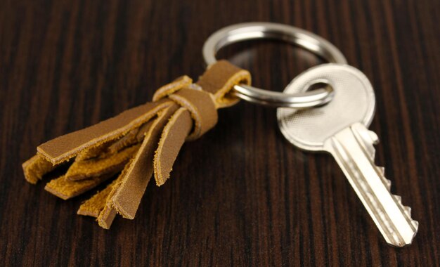 Key with leather trinket on wooden background