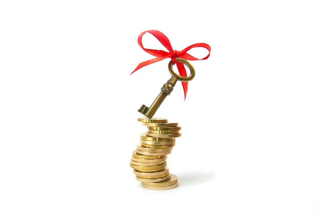 Key with a red bow on a curved stack of yellow coins isolated, concept key to financial success