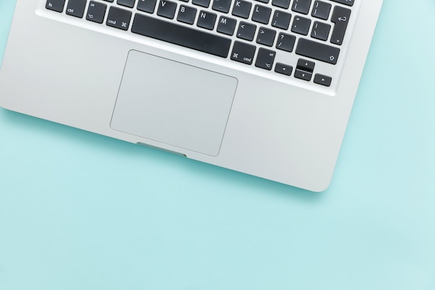 Keyboard laptop computer isolated on blue pastel desk background. Modern Information technology and sofware advances. Freelance home office programmer or designer workspace concept