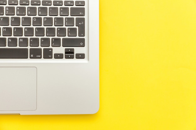 Keyboard laptop computer isolated on yellow desk background. Modern Information technology and sofware advances. Freelance home office programmer or designer workspace concept