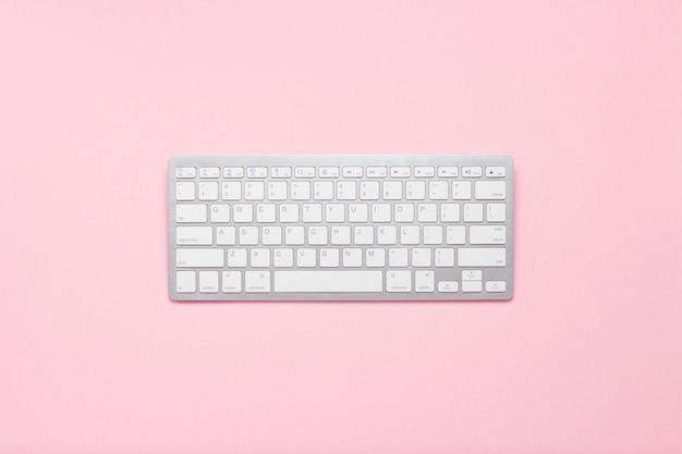 Keyboard on a pink background. Internet concept, writer, freelancer, journalist. Flat lay, top view.