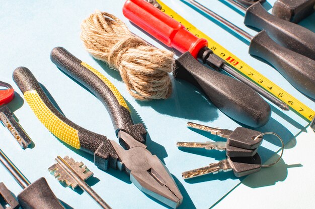 Keys and different tools on light blue background in sunlight