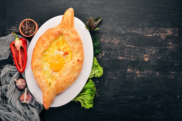 Khachapuri with egg and cheese Georgian cuisine On the old wooden background Free space for text Top view