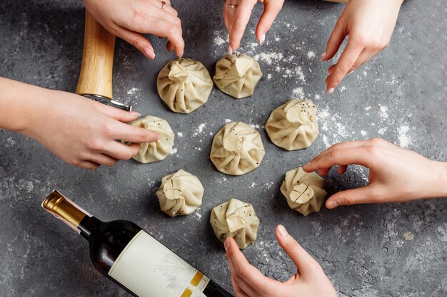 Khinkali, Georgian dumplings, traditional Georgian cuisine. Hands of people take khinkali from the side. Blue background, copy space.