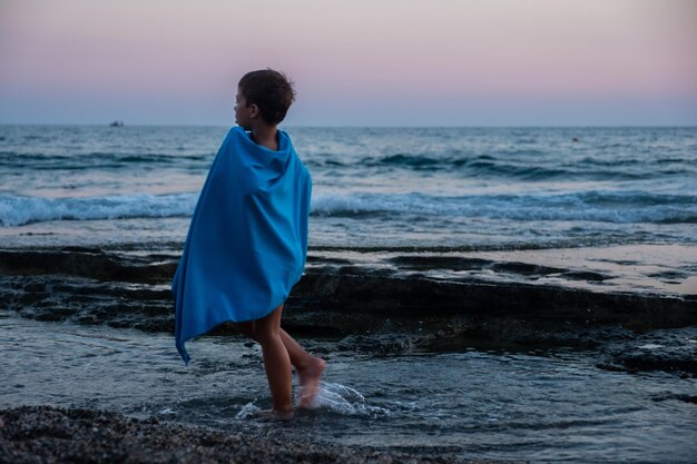 Photo kid at the beach while sunset