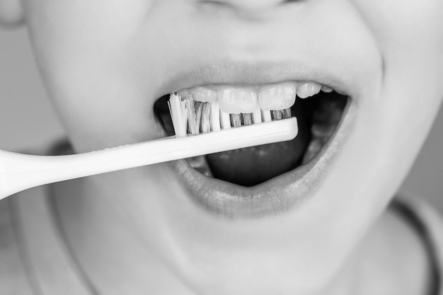 Kid boy brushing teeth Boy toothbrush white toothpaste Health care dental hygiene Black and white