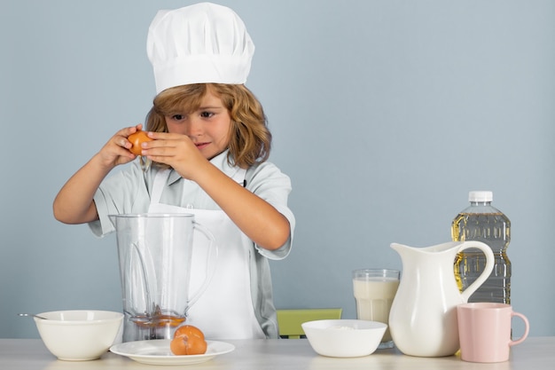 Kid boy in chef hat and apron cooking preparing meal little cook with vegetables at kitchen natural