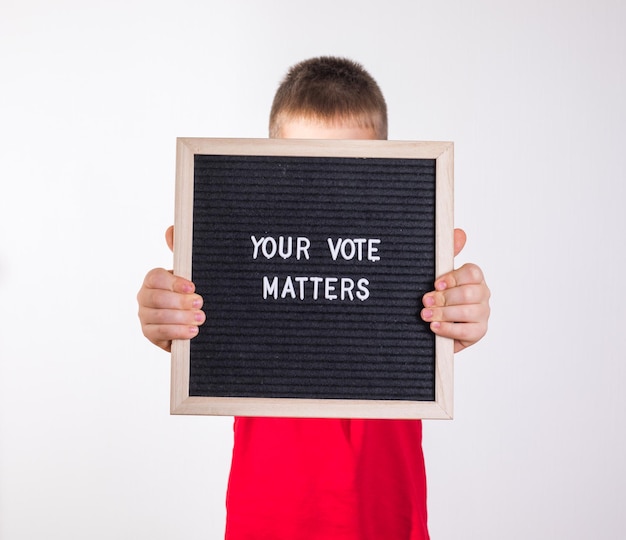 Kid boy holding letter board with text Your Vote Matters on white background