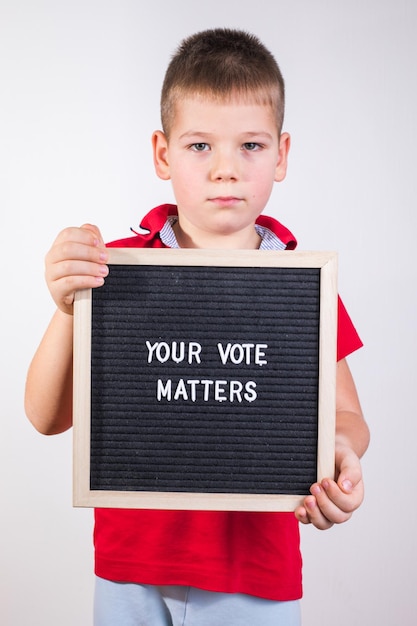 Kid boy holding letter board with text Your Vote Matters on white background