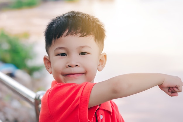 Kid boy pointing with finger  to the river, in a smiley face.