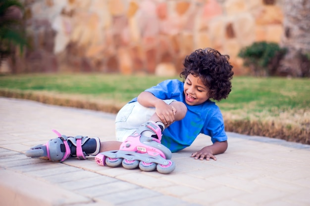 A kid boy on rollerskates fell down and feels pain. Children, leasure and healthcare concept