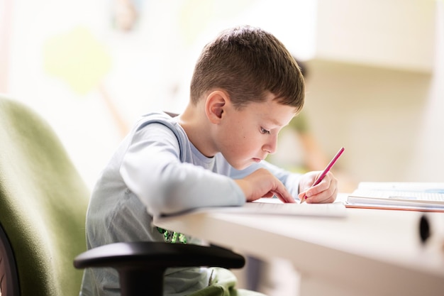 Kid boy studying at home and doing school homework distance learning education sitting at table