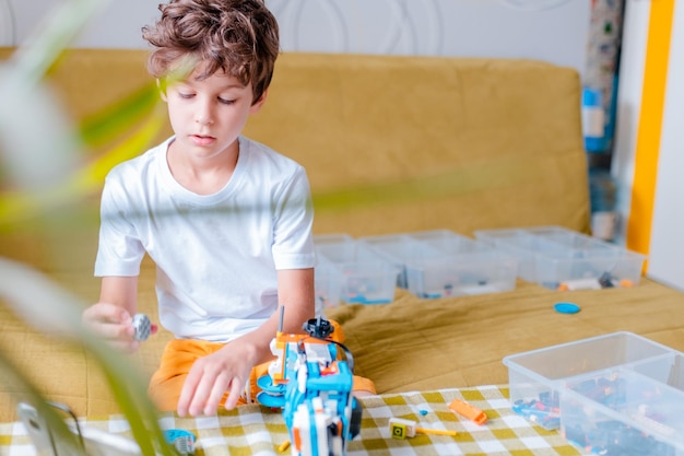 Kid collects robot from plastics details and programmed on tablet robotics