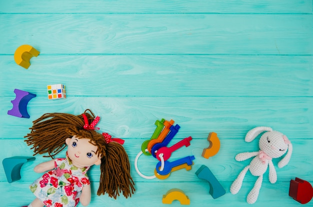 Kid doll with wooden building blocks on blue background