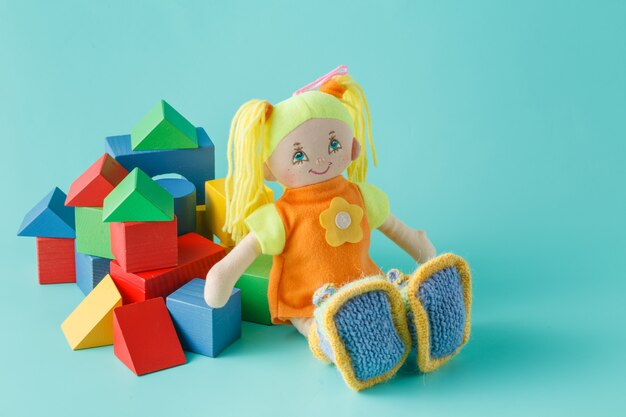 Kid doll with wooden building blocks on plain background