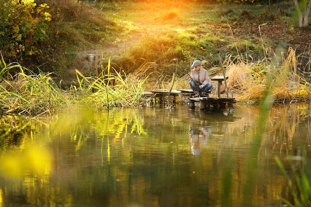 Kid fishing in a river sitting on a wood pontoon