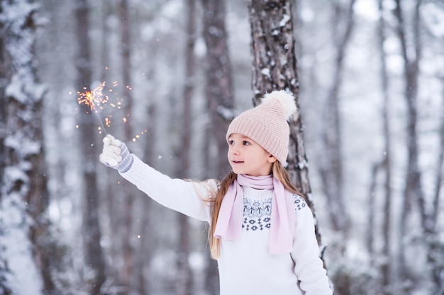 Kid girl holding firework outdoors over winter background