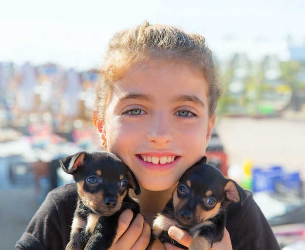 kid girl playing with puppy dogs smiling