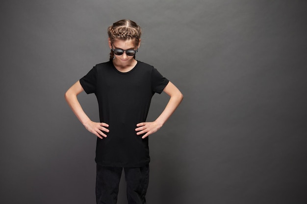 Photo kid girl wearing black t-shirt with space for your logo or design in studio over gray background