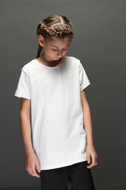 Kid girl wearing white t-shirt with space for your logo or design in studio over gray background