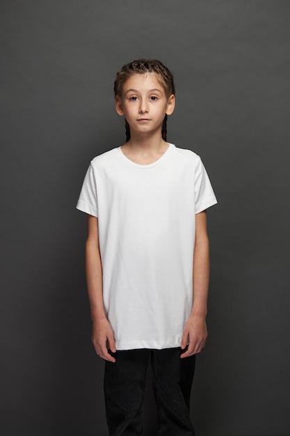 Kid girl wearing white t-shirt with space for your logo or design in studio over gray background