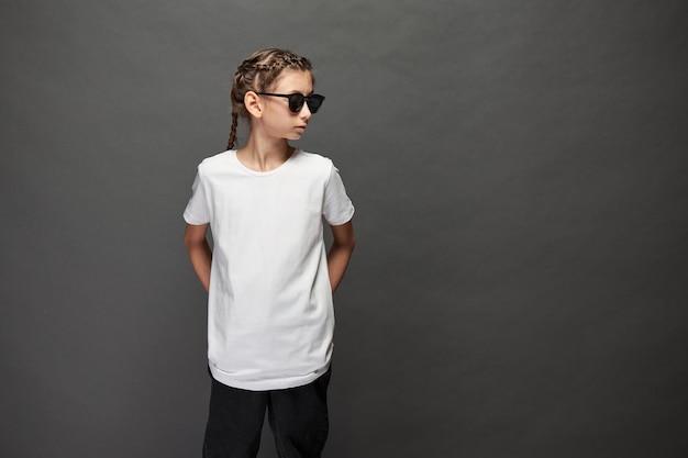 Kid girl wearing white t-shirt with space for your logo or design in studio over gray background