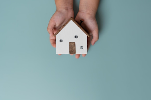 Kid hands holding small wooden house concept of living