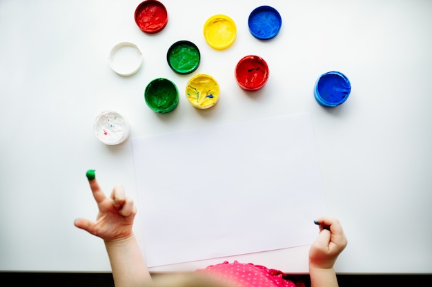 Kid hands start painting at the table with art supplies, top view